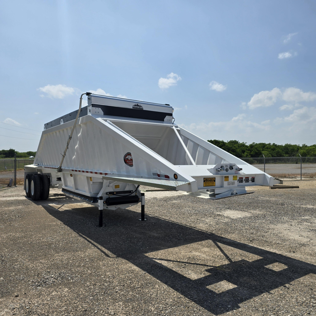 Dump trailer with white air ride dump bed and dual rear axles, no spare tire, on gravel lot; VIN tag and stock number visible.