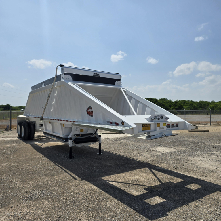 Dump trailer with white air ride dump bed and dual rear axles, no spare tire, on gravel lot; VIN tag and stock number visible.