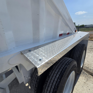 DT dump trailer side with diamond plate mudguard, dual tires, white painted steel body, side rail and wheel well on the dump bed.