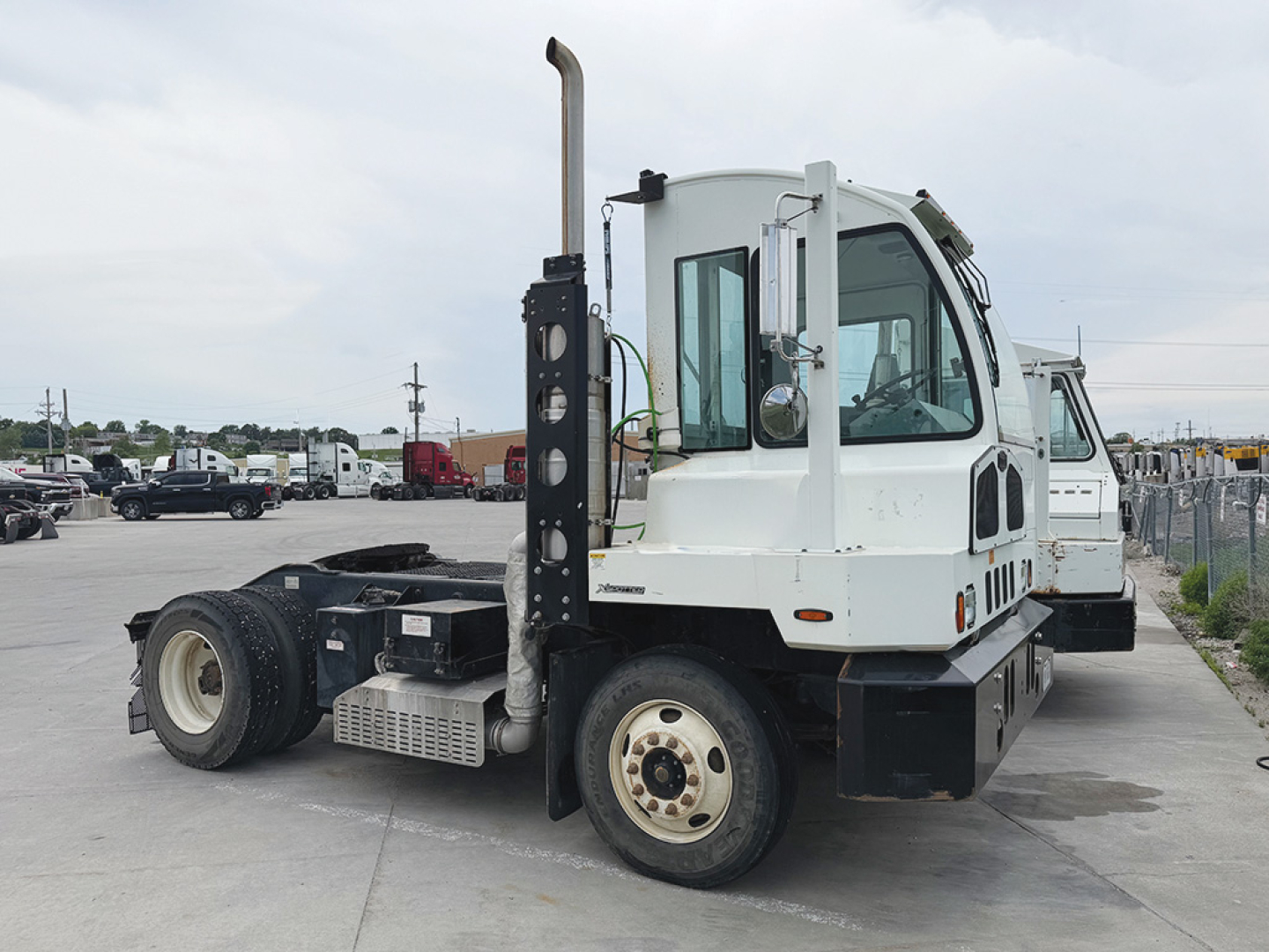 Autocar ACCT42 XSpotter yard truck side view showing cab, crane, and dual rear axles with white and black paint.