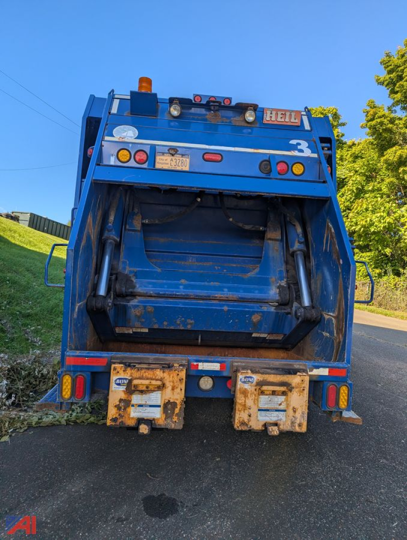 Back view of a blue 2011 Mack LEU TerraPro dump truck with rear ejector, visibility of hydraulic cylinders and tailgate hooks.