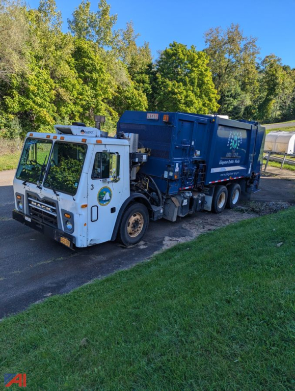 Mack LEU TerraPro refuse truck in blue in-yard side view showing box, cab and rear compactor unit with company logos.