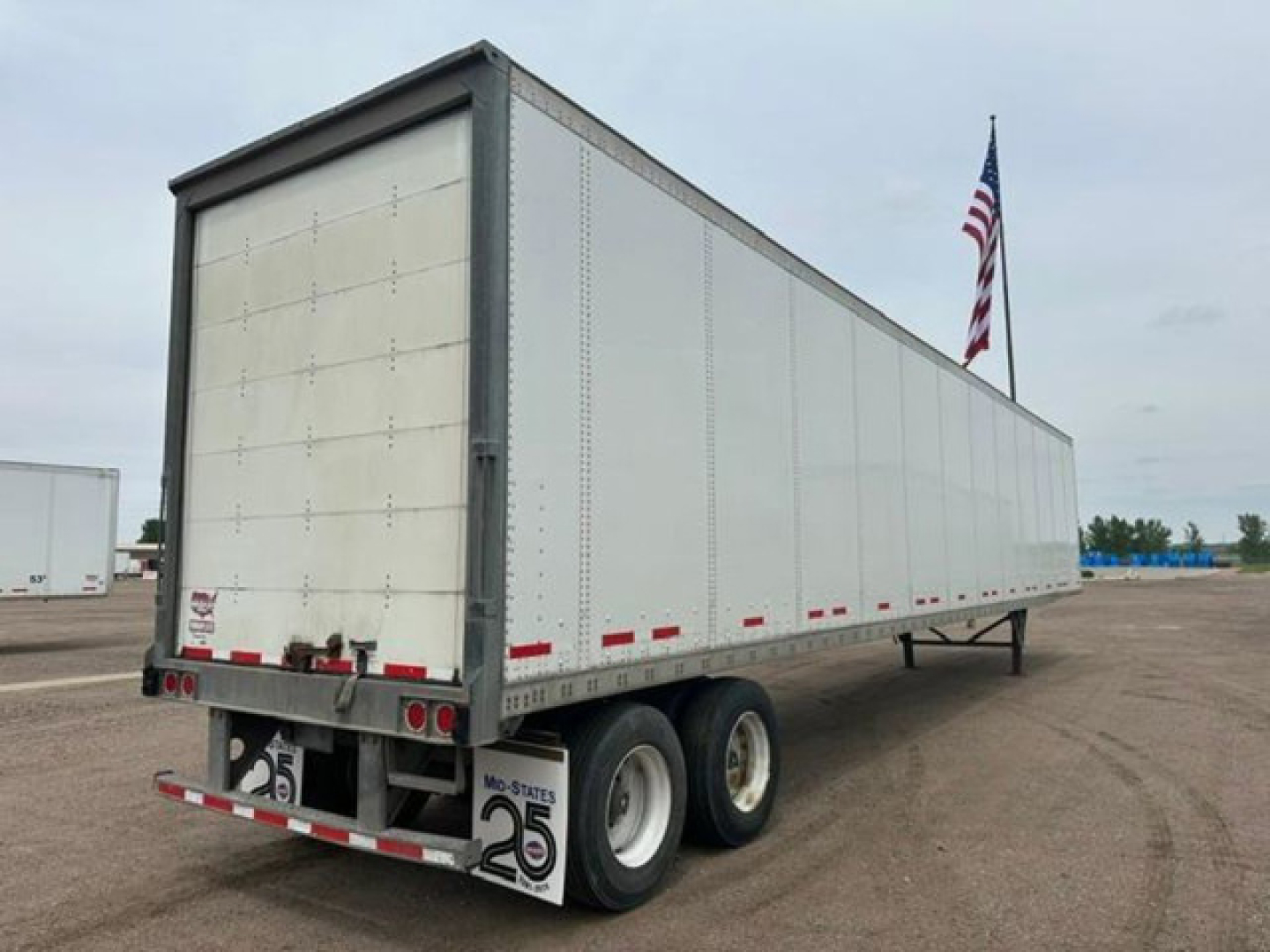 2016 Wabash cargo trailer side and rear showing dual-axle wheels, white exterior, red and white rear lights, and small warning labels.