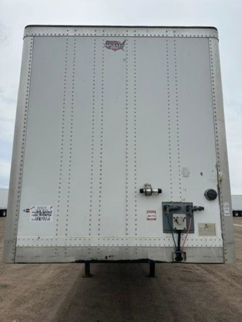 Rear view of a white 2016 Wabash van trailer showing a rear doors and electrical connections with stickers and a small circular vent.