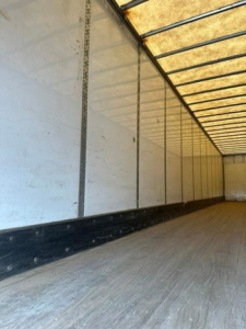 Trailer interior showing aluminum sidewalls and wooden floor in a cargo van trailer