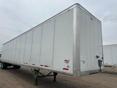 Trailer side view showing a white Wabash dry van with riveted aluminum panels and rear swing doors.