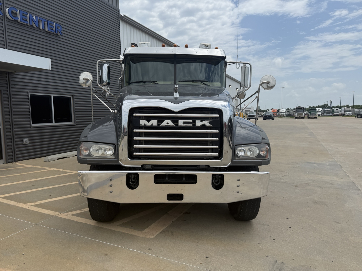 Front view of a 2023 Mack GR64F dump truck showing large chrome grille with MACK lettering, dual headlights, and chrome bumper.