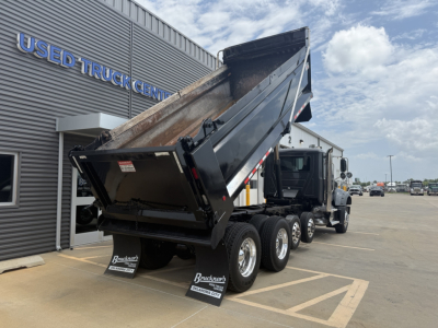 Dump truck bed raised showing Mack GR64F chassis and three rear axles at used truck lot.