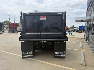 Dump truck bed of a 2023 Mack GR64F viewed from rear showing black dump body, tailgate, and two mud flaps with Buckner's Oklahoma City branding.