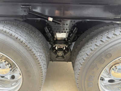 Dual rear wheels with heavy-duty suspension and undercarriage components visible between axles of a Mack GR64F dump truck.