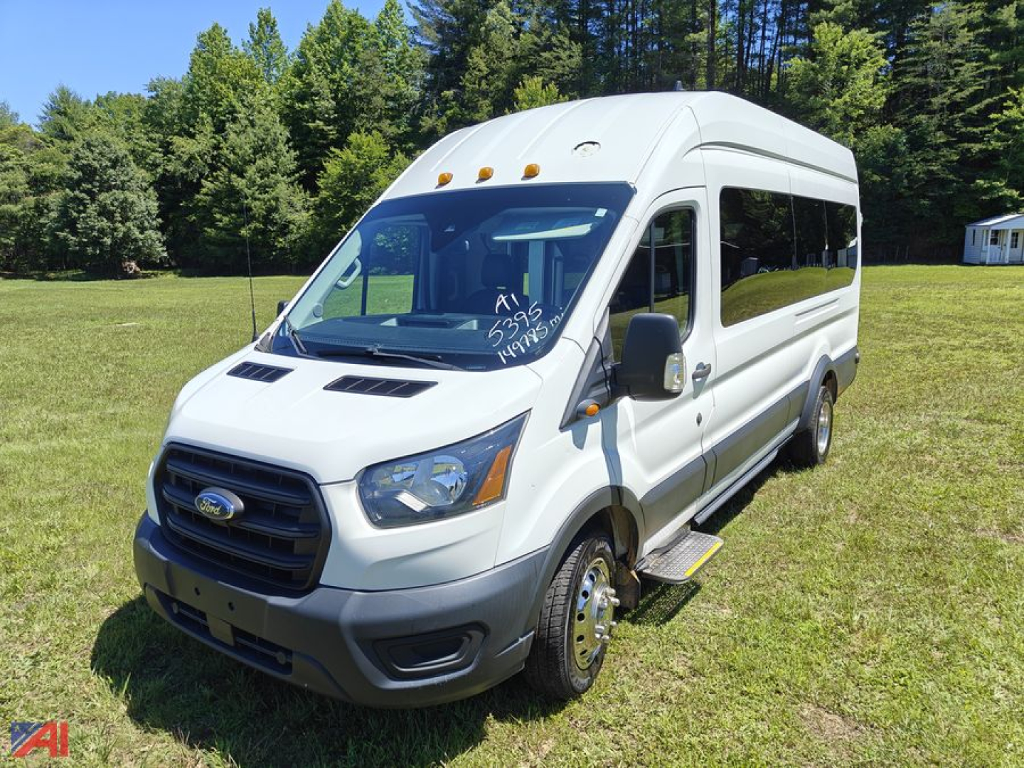 Ford Transit van with wheelchair lift, white, front grille and side ramp, side windows, text on windshield and side indicating wheelchair conversion.