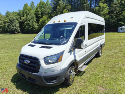 Ford Transit van with wheelchair lift, white, front grille and side ramp, side windows, text on windshield and side indicating wheelchair conversion.