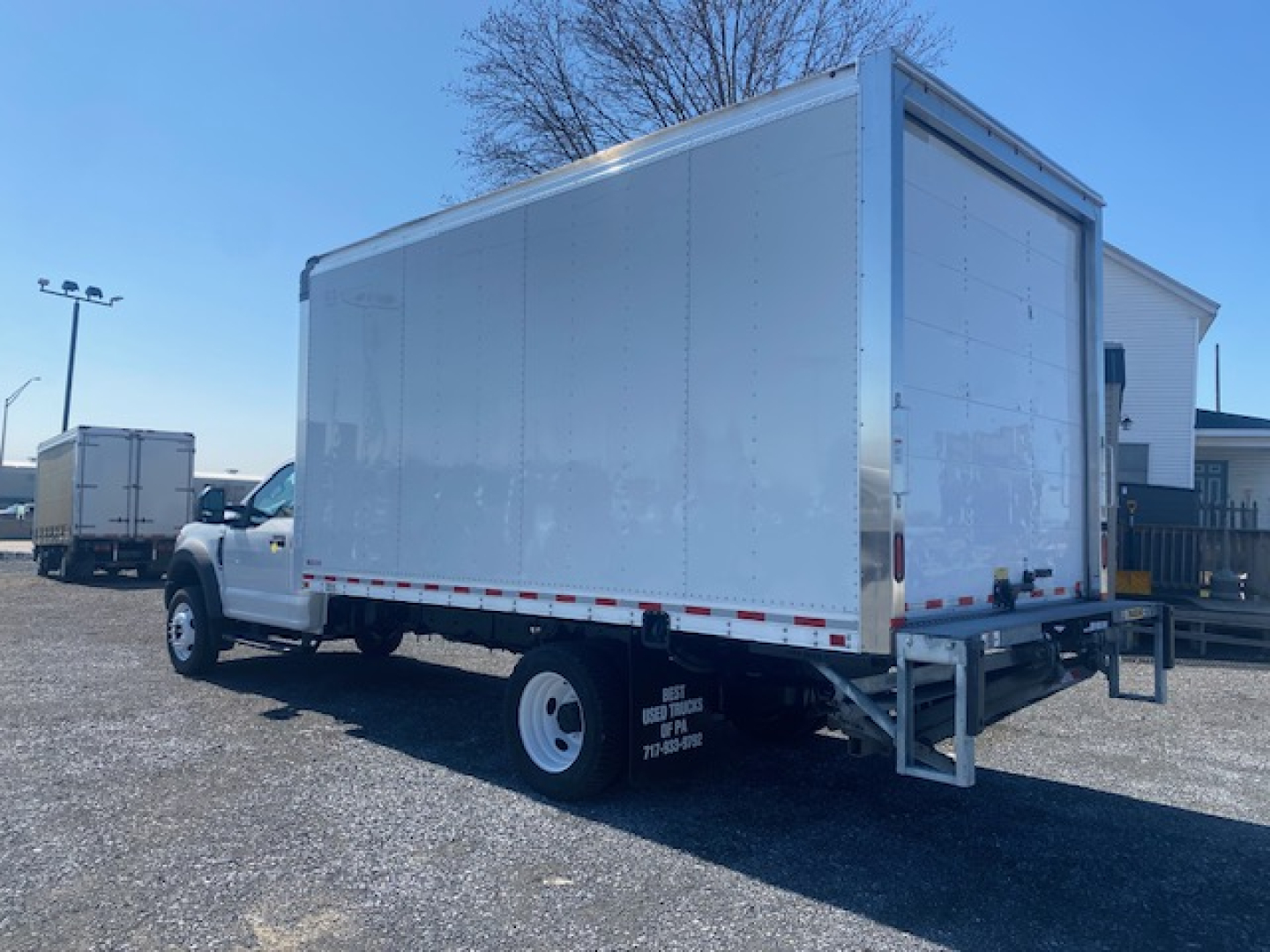 Ford F-550 box truck side and rear view showing large cargo box and dual rear wheels with white cab and metal framework.
