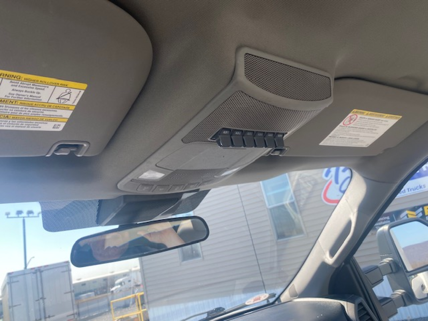 Ford cabin interior showing overhead console with warning labels and rearview mirror.