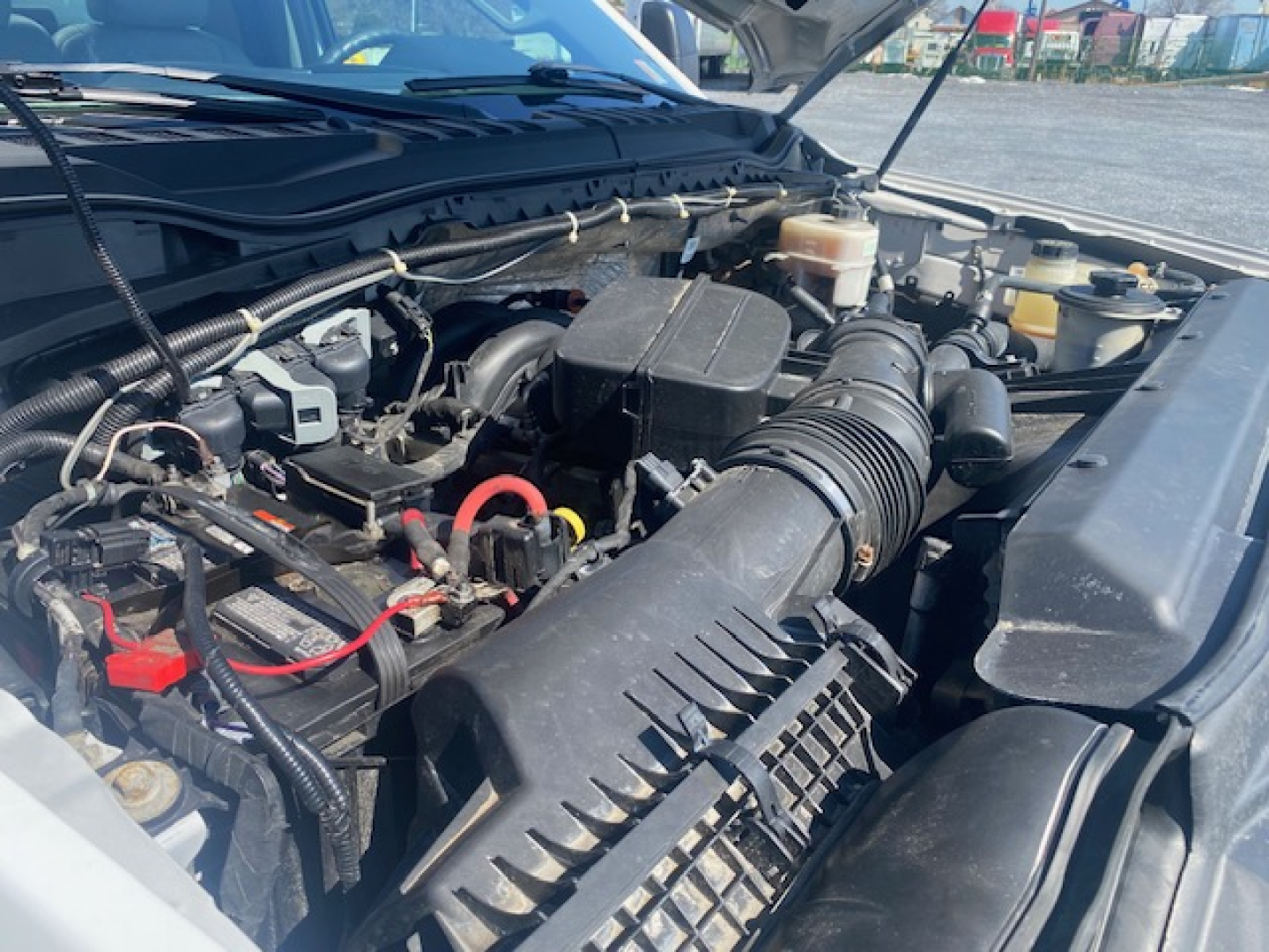 Ford F-550 engine bay showing air intake, battery, and various hoses under the hood.