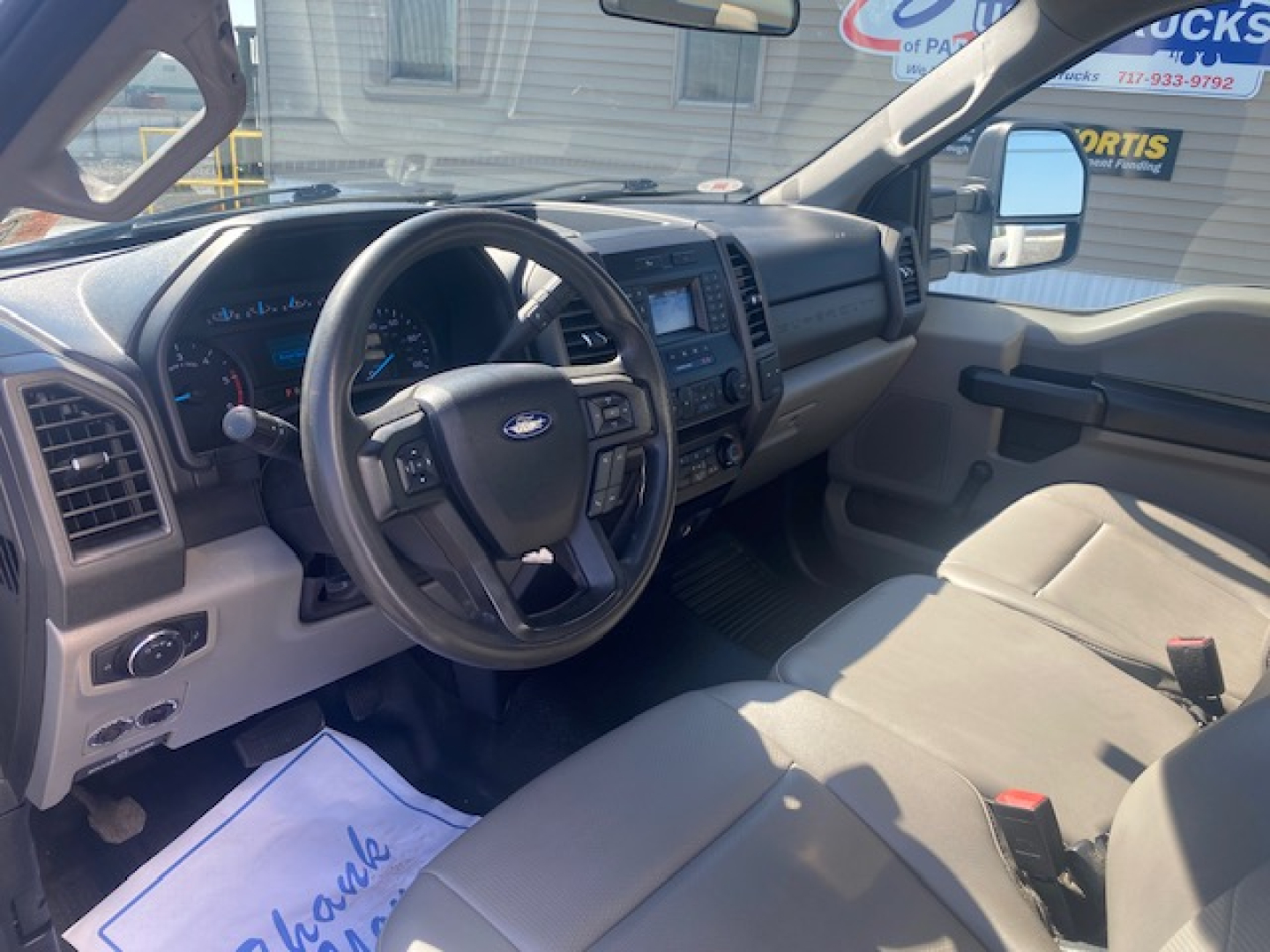 Ford F-550 cab interior showing steering wheel and dashboard with beige seats.