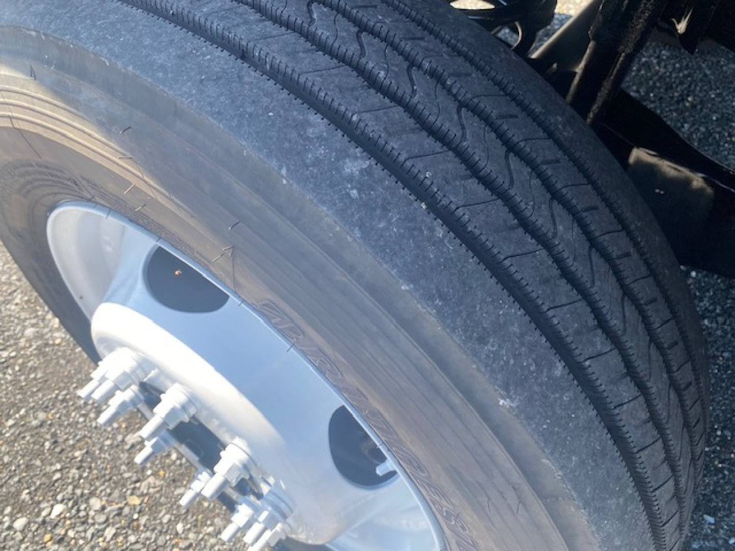 Ford F-550 wheel and tire close-up showing dual rear axle hub and lug nuts with snow/dust on tire treads.