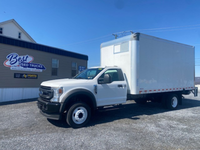 Ford F-550 box truck in front of dealership showing white cab and large box body.