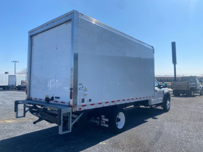 Ford F-550 box truck rear and side view showing cargo box and white wheels with reflective tape along the sides.