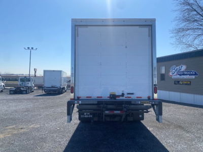 Ford F-550 box truck rear view showing cargo doors and bumper with taillights and hitch; dealership lot in background.