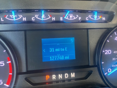 Dashboard view of a Ford F-550 showing blue-lit gauges, center digital display reading '31 mi to E' and '127748 mi' with gear indicator PRNDM.
