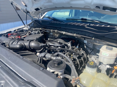 Ford F-550 engine bay visible under open hood with various hoses and reservoir caps; no legible text readable on components.