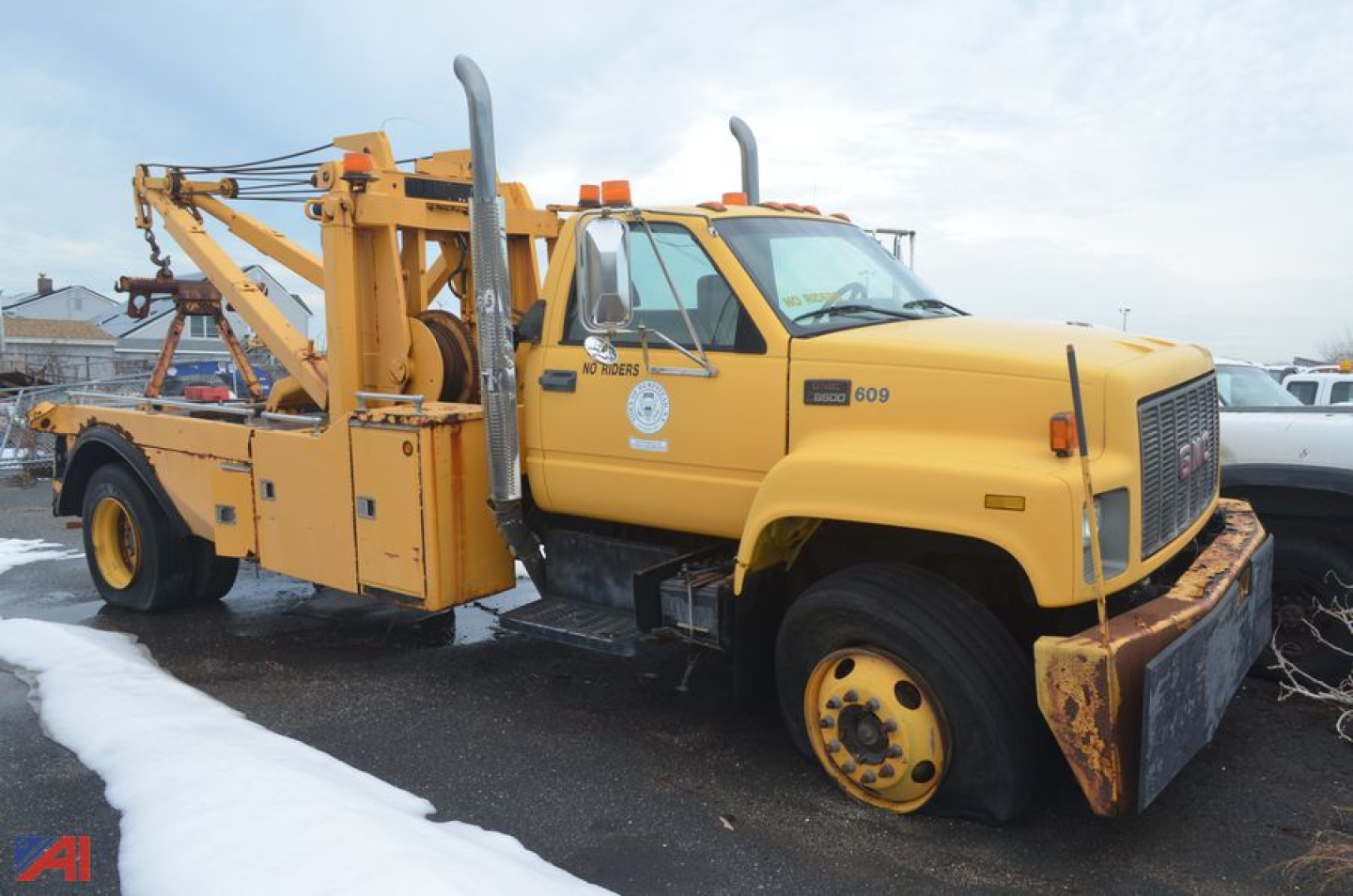 2001 GMC C7500 tow truck with mounted rotator and equipment on flatbed, yellow paint, visible front bumper and wheels.