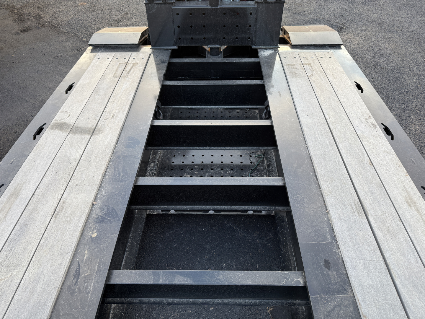 Trailer frame top view showing central bolster with multi-leaf structure and aluminum deck planks on either side.