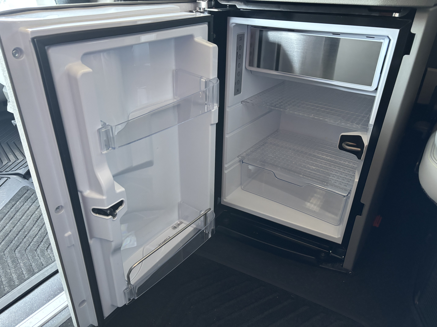 Volvo VNL64T860 truck cab showing open refrigerator and empty freezer compartment inside the cab, with shelves and door shelves visible.