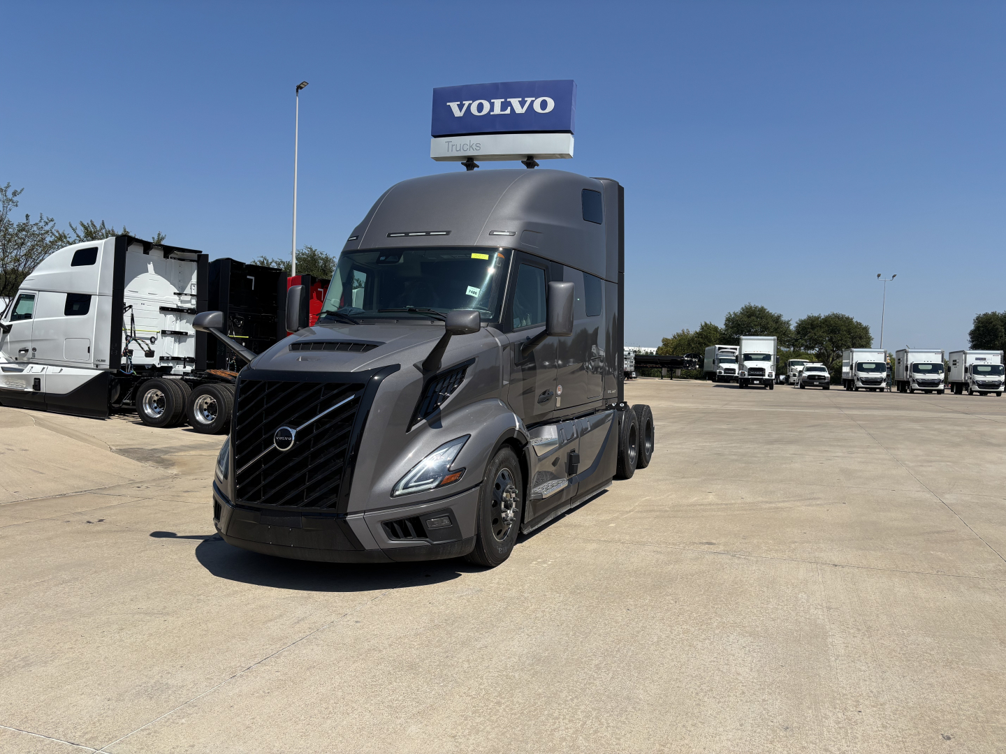 Volvo VNL64T860 semi-truck in showroom lot with Volvo sign on top, front left view showing black grille and aerodynamic cab.