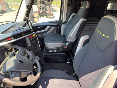 Interior of 2026 Volvo VNL64T860 cab showing steering wheel, dashboard, and driver and passenger seats with Volvo logos on headrests.