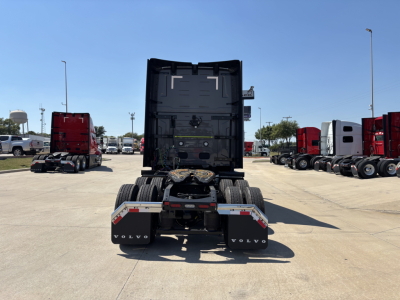 Rear view of a new Volvo VNL64T860 tractor showing fifth wheel, rear bumper, and dual rear axles in a truck lot.