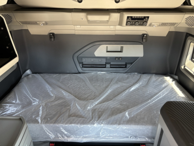 Volvo VNL64T860 sleeper cab interior showing cargo area with plastic-covered mattress and storage compartments on wall panel