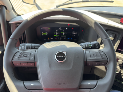 Volvo VNL64T860 interior steering wheel with digital instrument cluster visible through steering column.