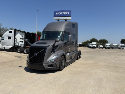 Volvo VNL64T860 semi-truck in showroom lot with Volvo sign on top, front left view showing black grille and aerodynamic cab.