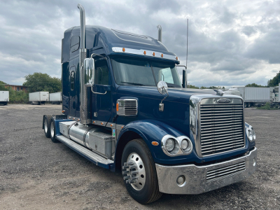 Freightliner Coronado truck shown in blue with chrome grille and dual exhaust stacks, sleeper cab, front view.
