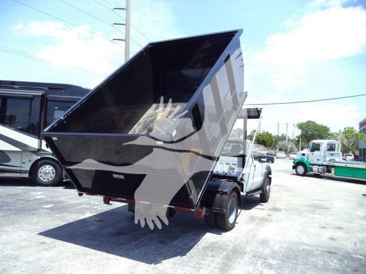 Ford F-550 dump bed truck with hydraulic dumper raised, visible text not legible on components.