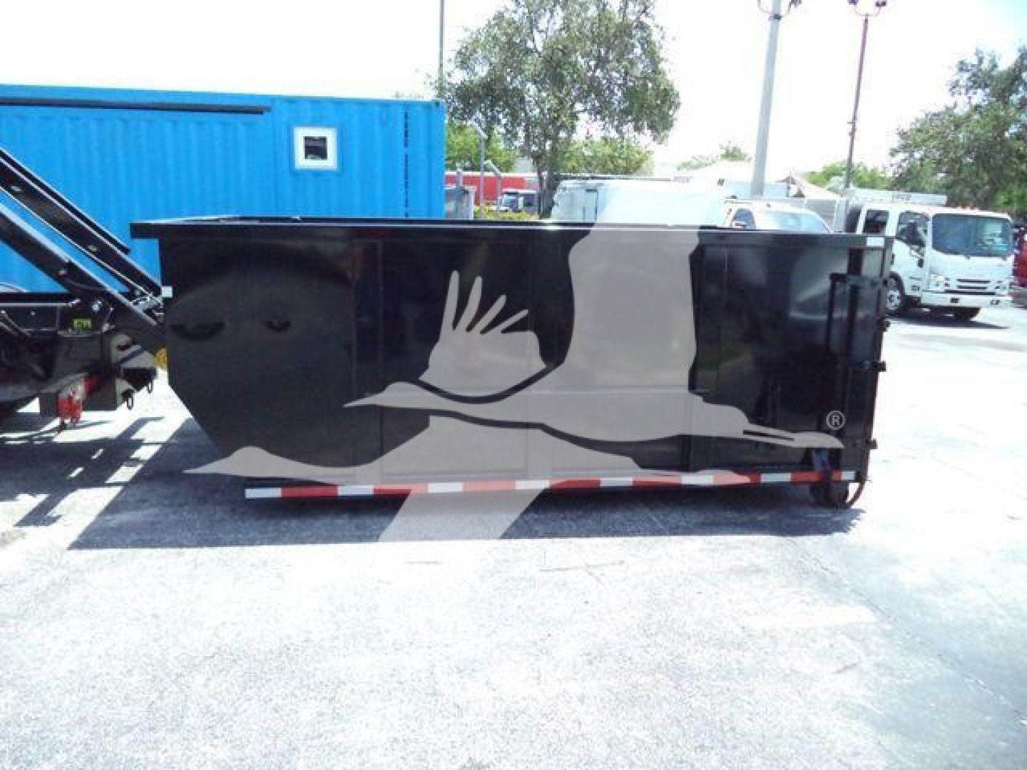 Rolloff truck container in black with white graphic of a winged hand logo on side, parked in lot.