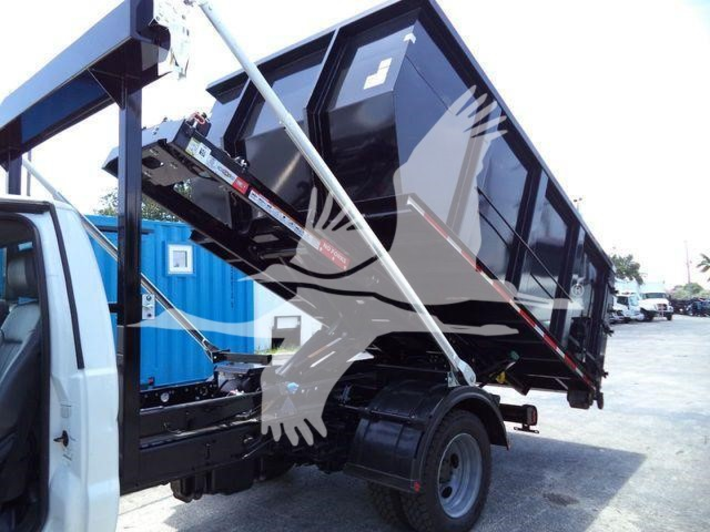 Truck bed tilt mechanism on a 2016 Ford F550 roll-off truck showing the raised dumping container and hydraulic supports.