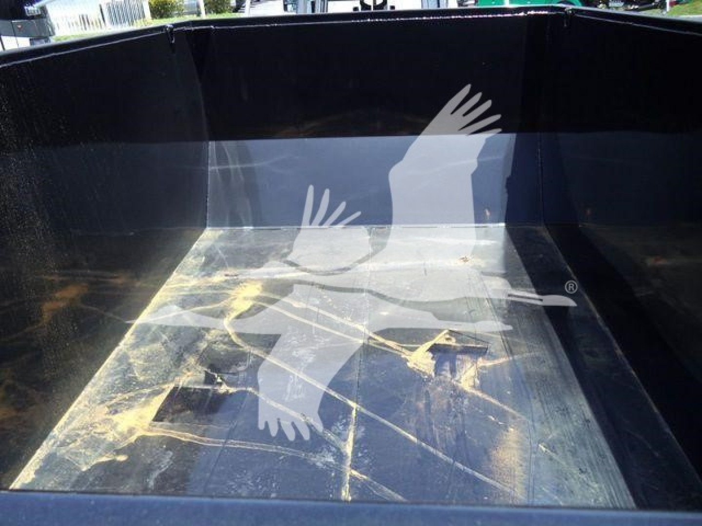 Truck bed of a 2016 Ford F550 roll-off truck showing a black metal cargo bed interior with dirt and scuff marks.