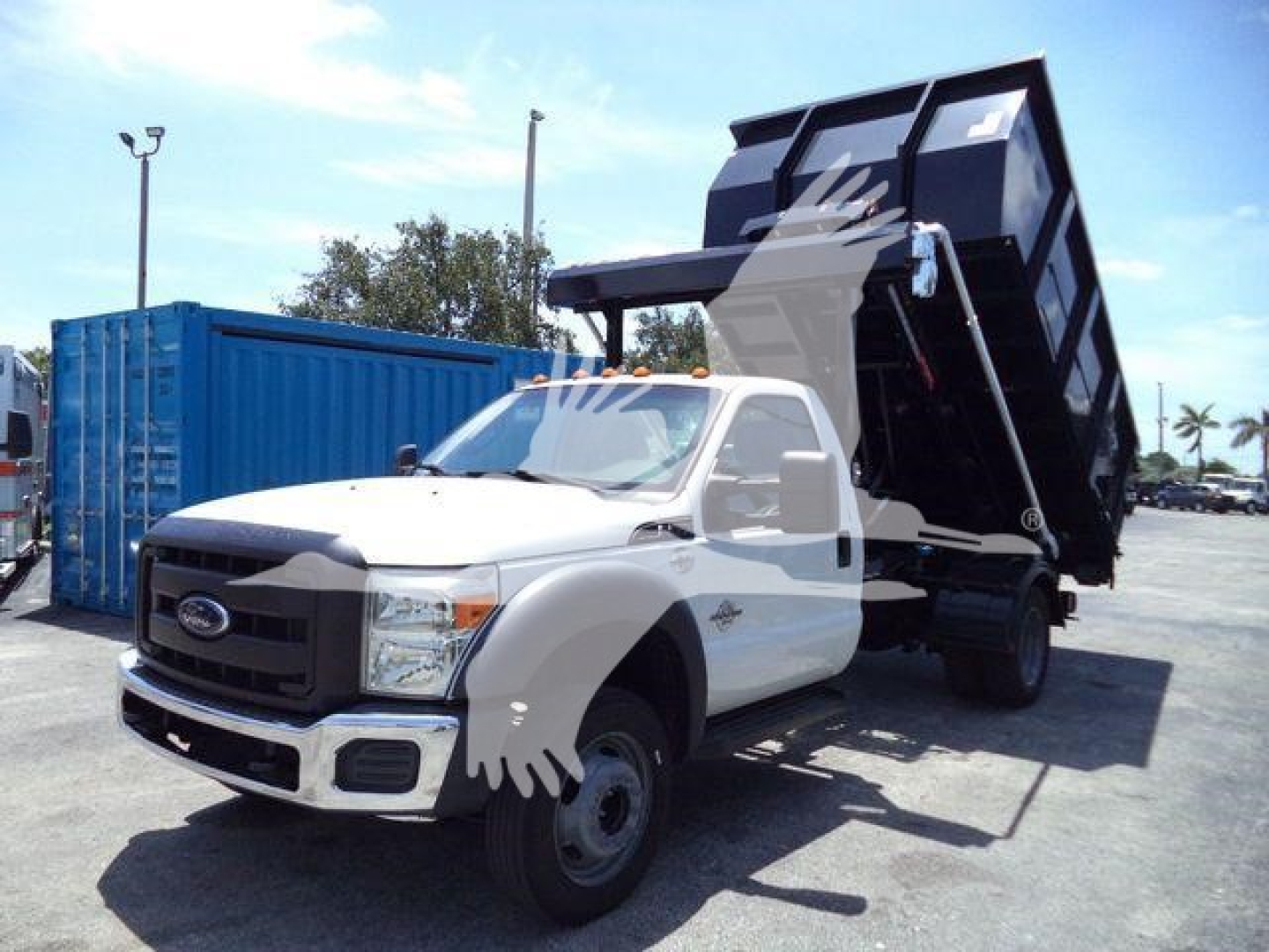 Ford F-550 dump truck in raised bed with cab front and grille visible. Stock number T58029FM listed. Side view shows rollover truck with hydraulic dump bed in raised position.