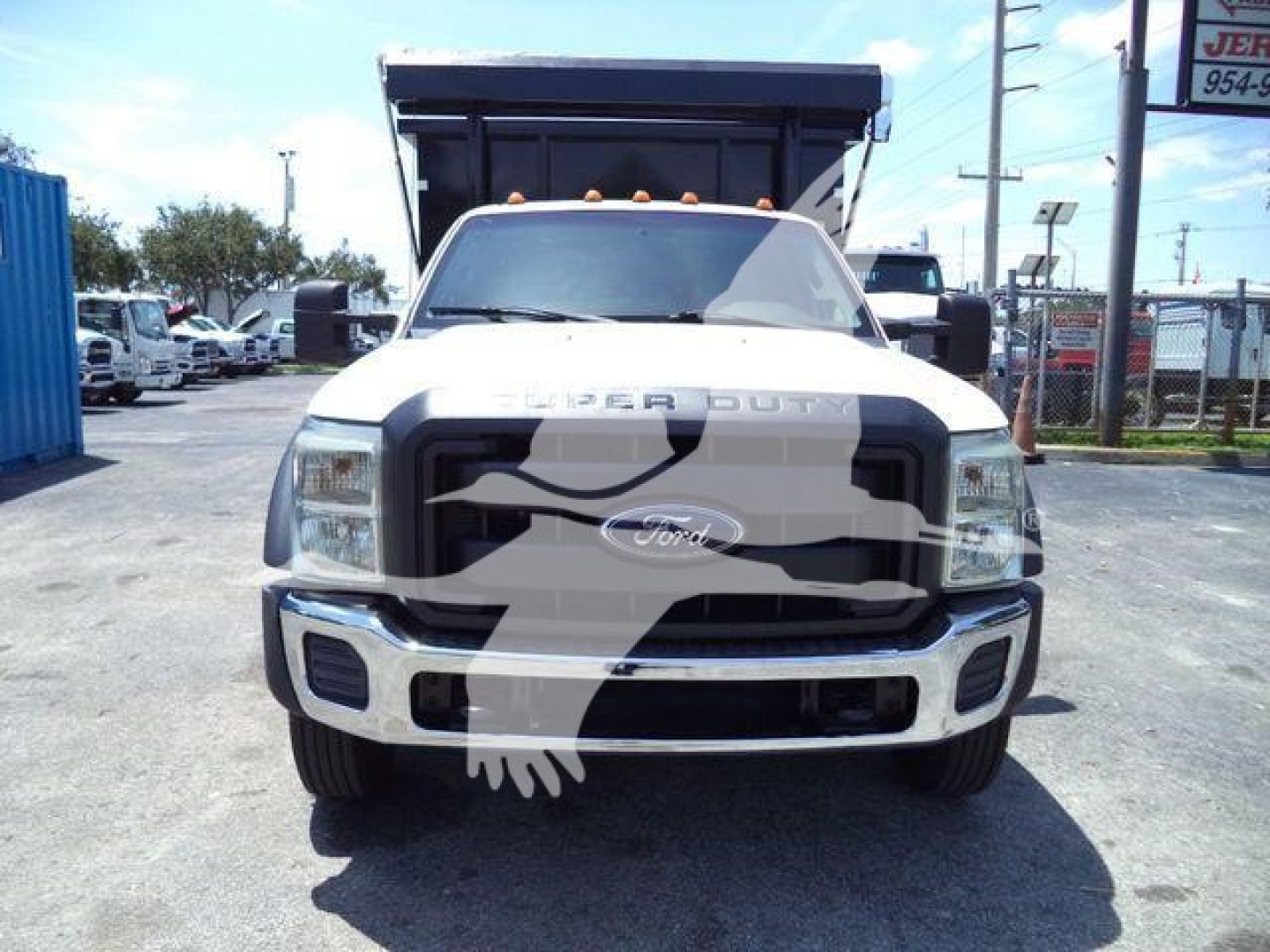Ford F-550 dump truck front view with 'FORD' emblem, chrome grille, headlights, and dump bed in the background.