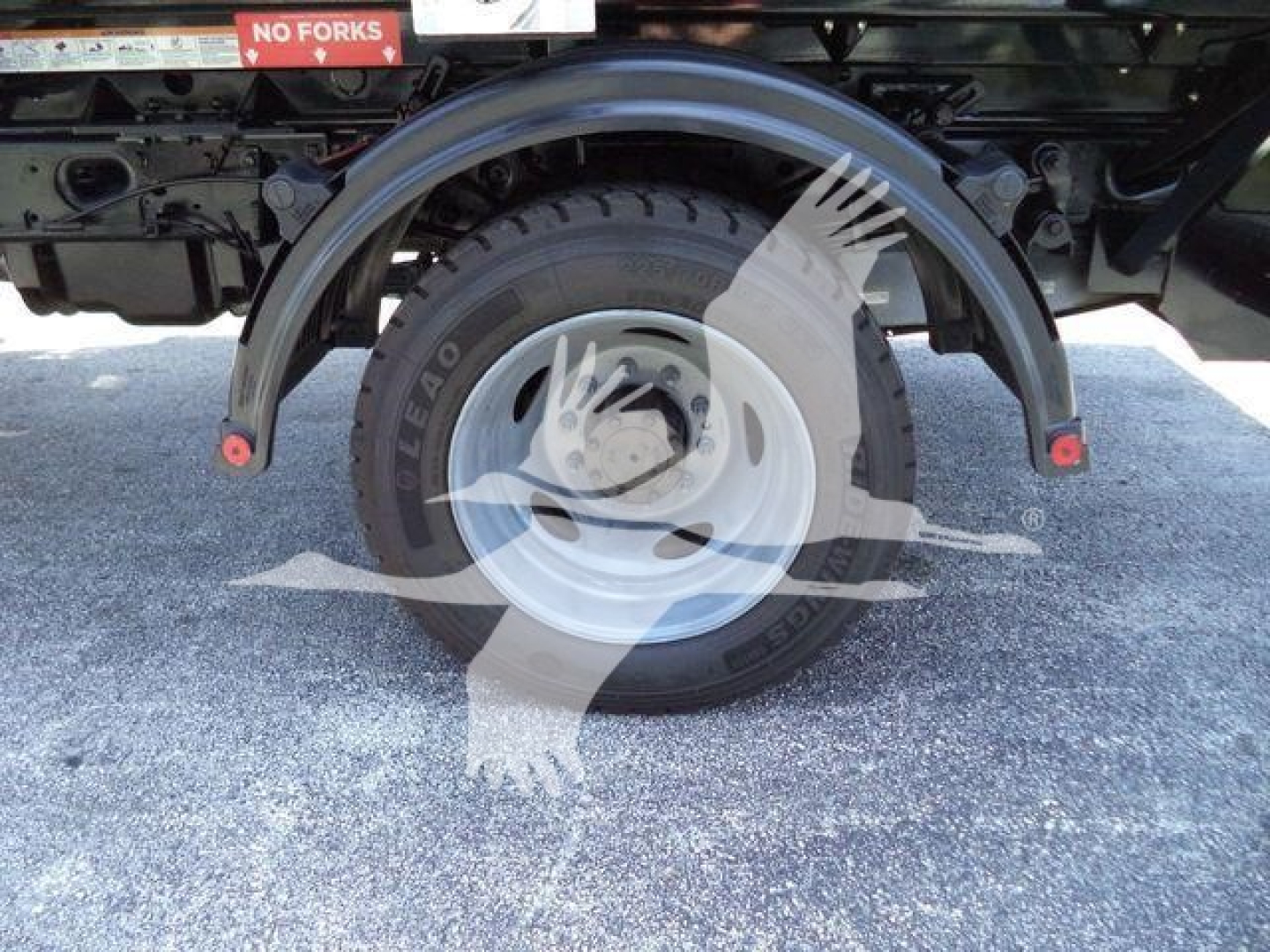 Rear wheel with fender and spare tire showing 'NO FORKS' sign and metal truck frame undercarriage.