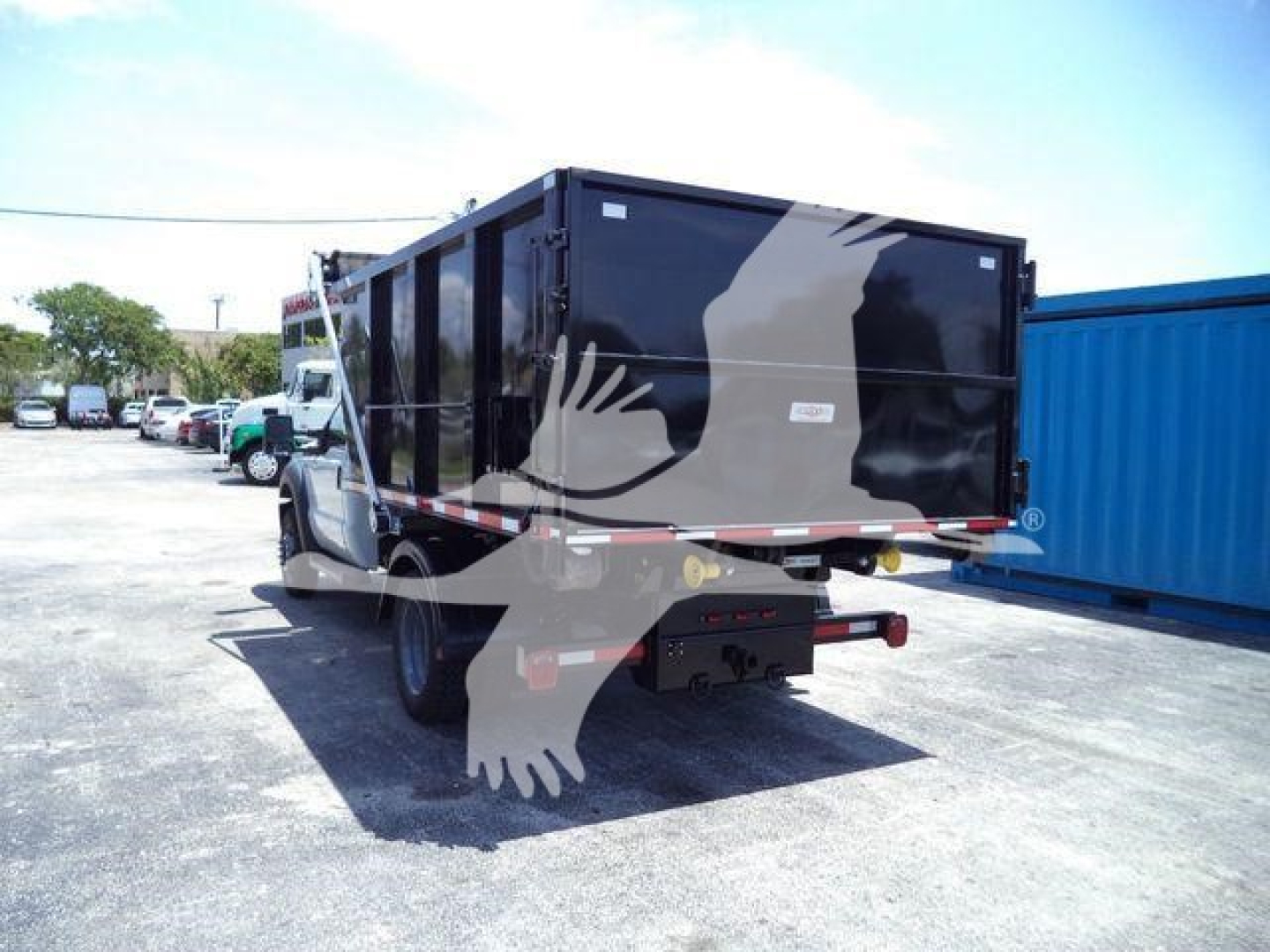 Truck bed or dump body mounted on Ford F-550 rear view showing black roll-off container.