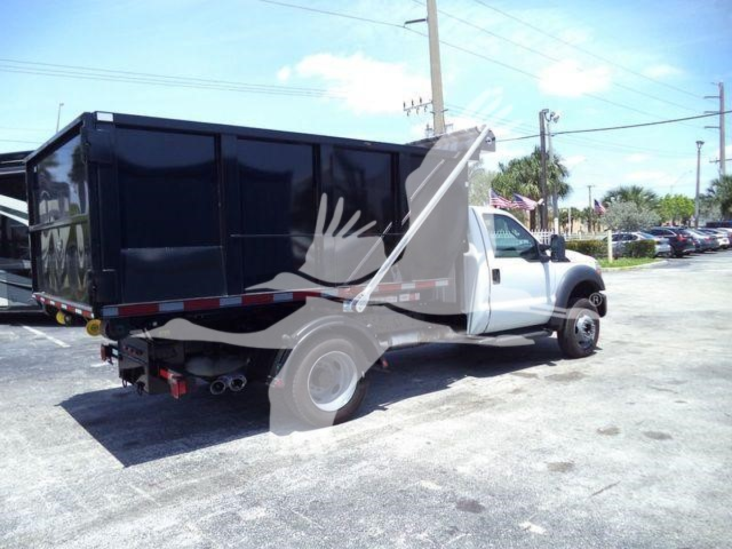 Ford F-550 roll-off truck in service showing cargo bed and black dump body with white cab.