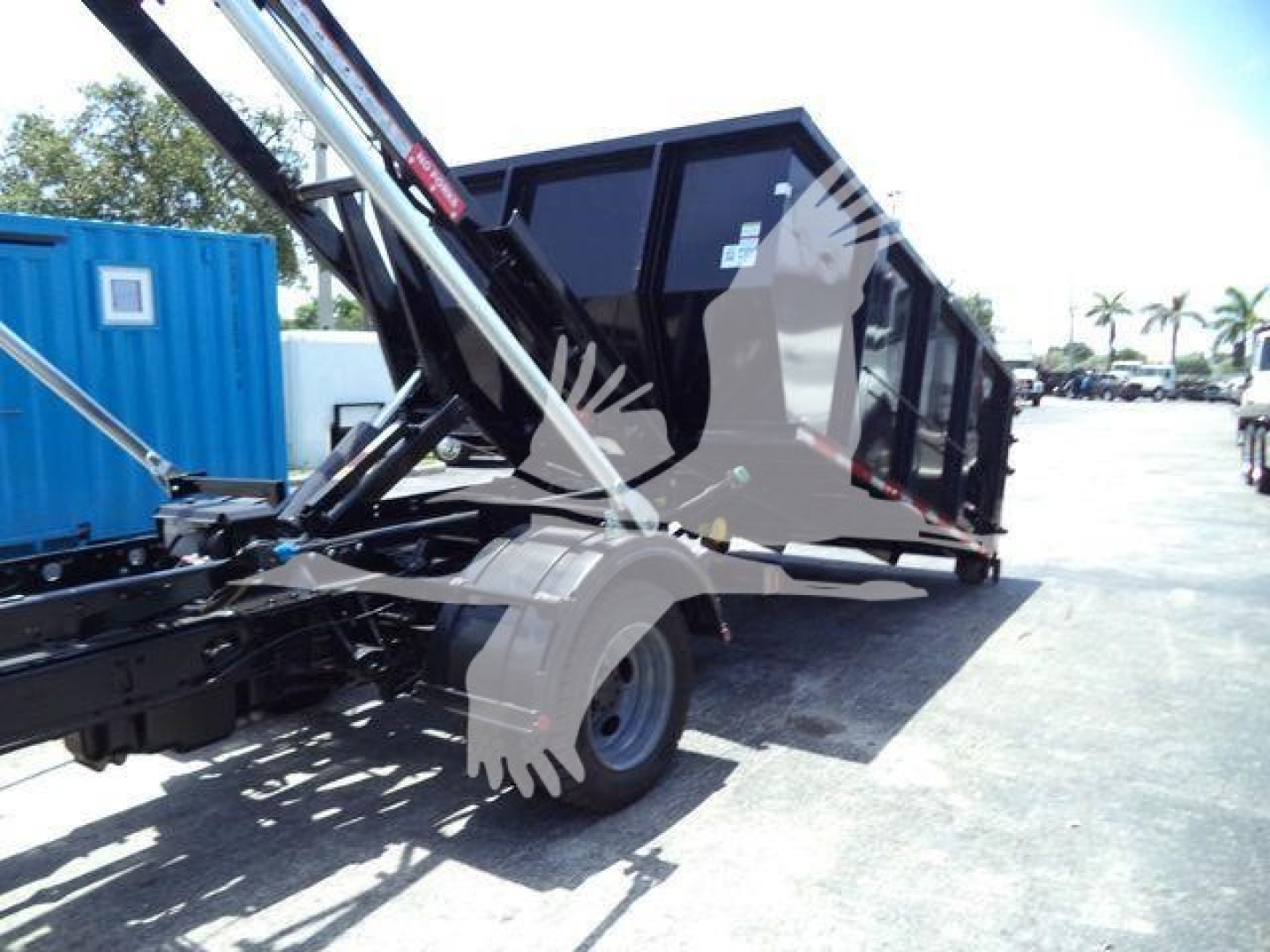 Ford F-550 rolloff truck with a hydraulic dumping trailer in a yard; no legible labels visible on the image itself.