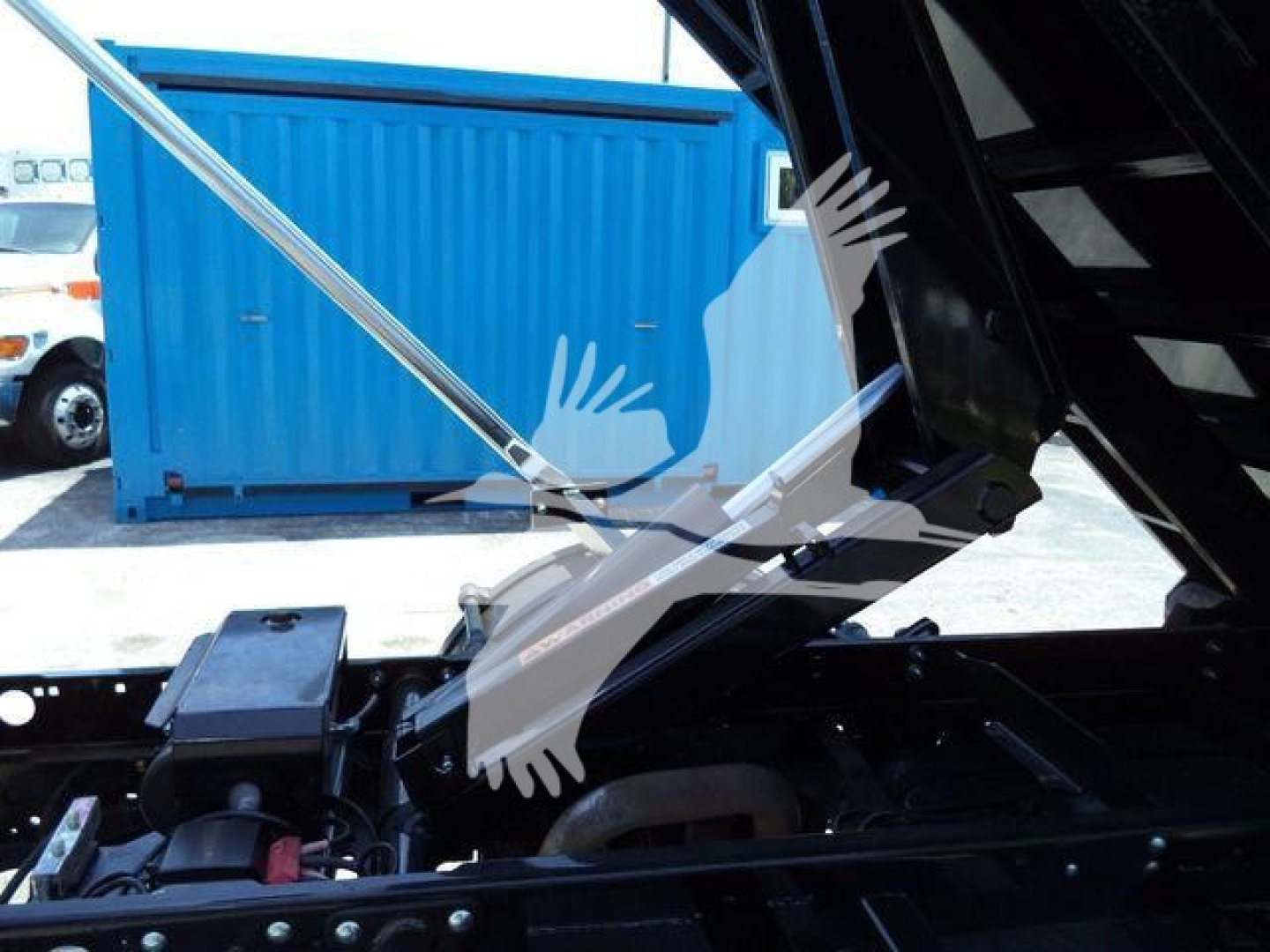 Ford F-550 roll-off truck chassis showing hydraulic components and bed in open position.