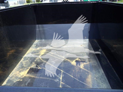 Truck bed of a 2016 Ford F550 roll-off truck showing a black metal cargo bed interior with dirt and scuff marks.