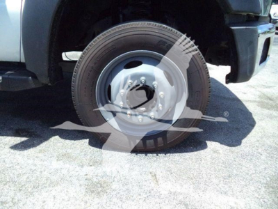 Wheel and front fender of a 2016 Ford F550 rolloff truck showing steel wheel with hub and tire, partial suspension and wheel well.