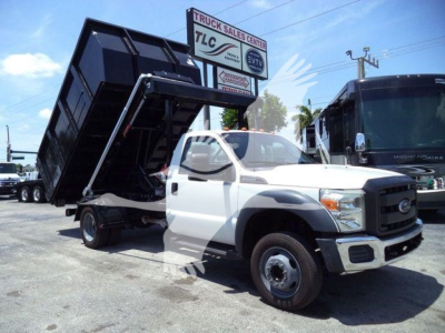 Ford F-550 dump truck in service with elevated black dump bed at a truck lot.